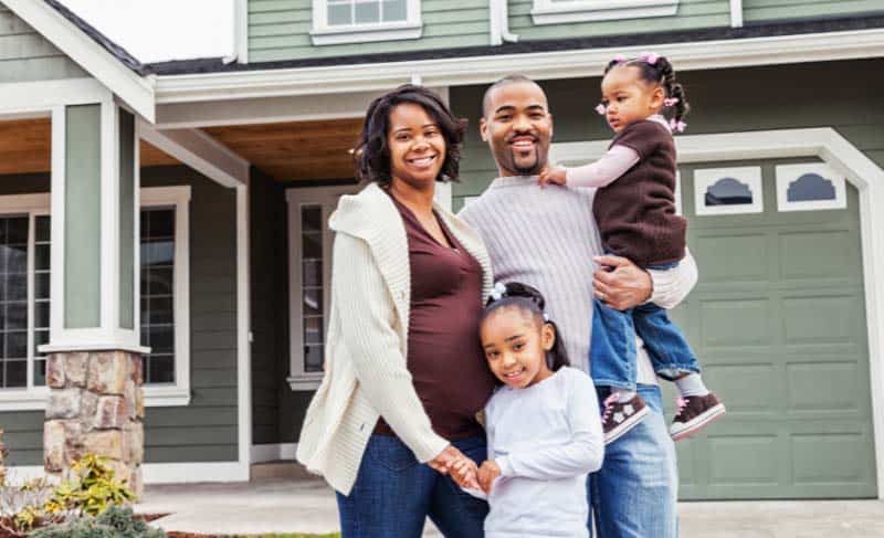 A family of four standing in front of a new home