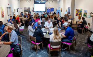 Conference room full of people at tables talking together